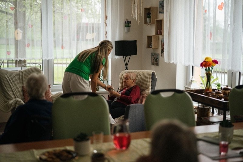 A carer attending to residents in a care home day room